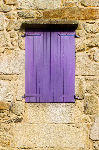 Cottage window, closed purple shutters, stone wall. Muros, A Coruña province, Galicia, Spain. Copy space on the lower side of the image.