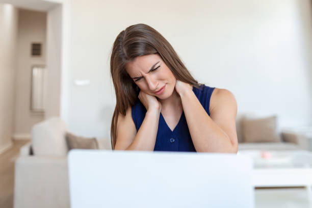 istock Feeling exhausted. Frustrated young woman looking exhausted and massaging her neck while sitting at her working place 1395465530