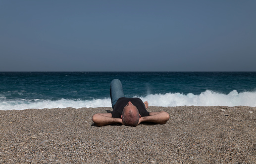 Adult man lying down on beach