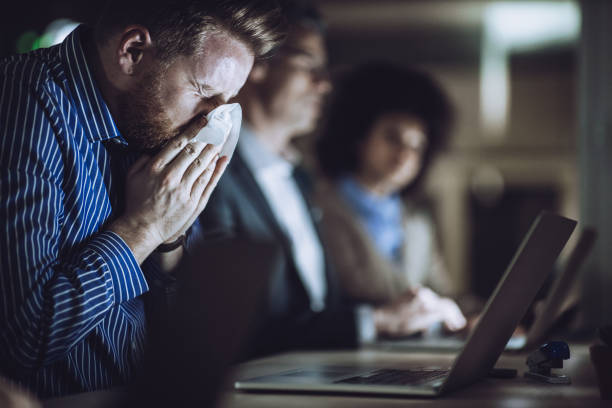 istock Ill businessman blowing nose while working late in the office. 1395467417