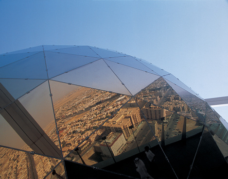 Reflection of downtown Riyadh and desert in The Globe at the top of the Faisaliah Center, Saudi Arabia. (notice Arab man on viewing deck in bottom centre of photo.)