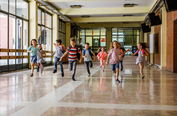 istock Large group of elementary students running in the school hallway. 1395467798
