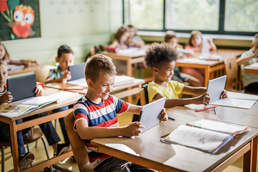 Smiling elementary student using touchpad on a class at school.