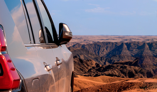 Close-up of a vehicle in the sand before a cliff.  Moon valley. Africa. Namibia