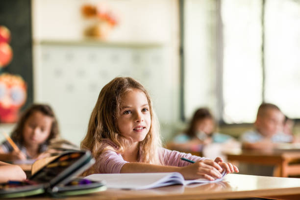 istock Smiling schoolgirl attending a class in the classroom. 1395468452