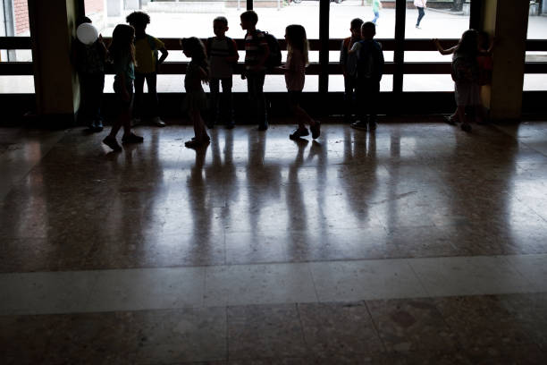 istock Silhouettes of large group of elementary students in a hallway. 1395468622