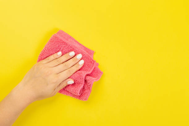 istock A housewife's hand holds a rag for dusting or washing. Empty space for text or logo on a yellow background. Early spring or regular cleaning. Cleaning and cleaning concept. 1395468693
