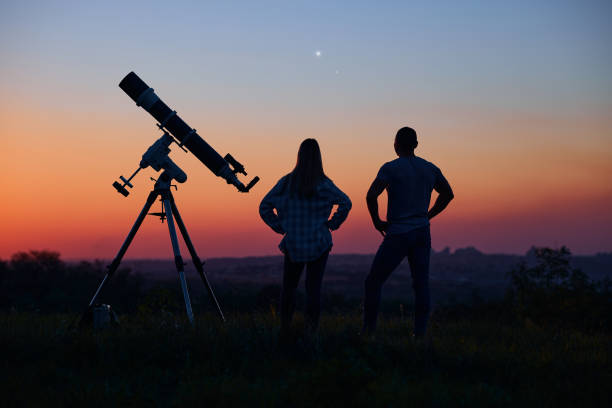istock Couple stargazing together with a astronomical telescope. 1395471541