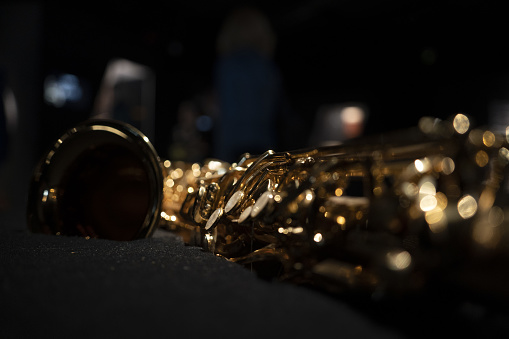 Confident female brunette student practicing flute with brass band. Teenage girl is looking away while blowing into woodwind instrument. She is playing music with friends in classroom.