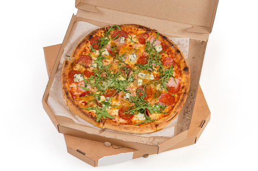 Round pizza with salami in open packaging in the form of the special cardboard box lies on the similar closed box, top view on a white background