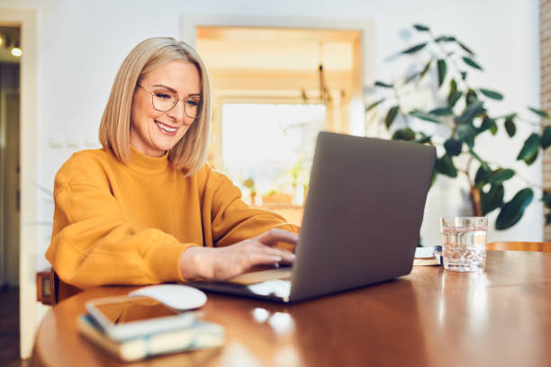 istock Cheerful mature woman working sitting at dinning table working from home office 1395474788