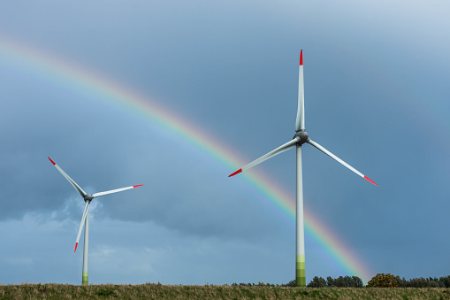 Two wind turbines on a field in Northern Germany with rainbow