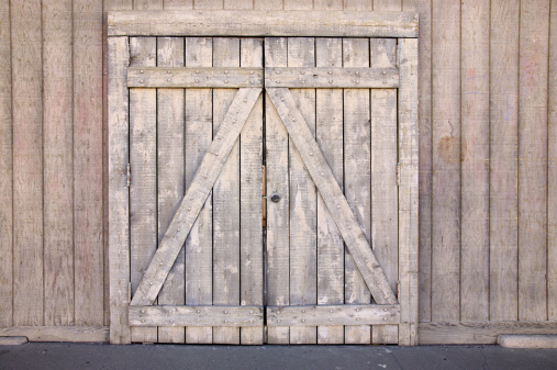 Weathered wood doorway in wooden wall.