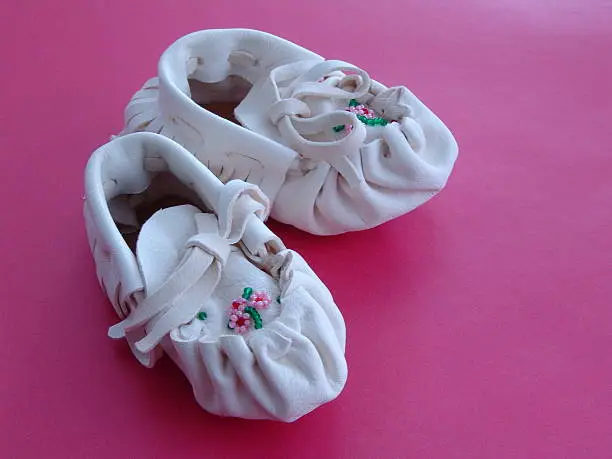 A pair of white Native American beaded baby moccasins