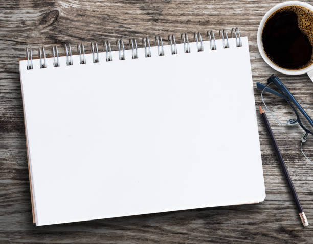 istock Blank notebook with pencil, glasses,coffee cup and flower on wood background 1395484434