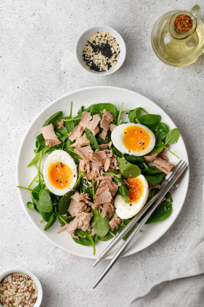 sałatka z tuńczyka z gotowanym jajkiem i szpinakiem na białym talerzu. dieta ketonowa, zdrowa żywność. świeża salaterka. obiad. widok z góry - spinach salad fork low carb diet zdjęcia i obrazy z banku zdjęć