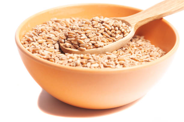 istock Wheat grains in bowl with wooden spoon isolated on white background. 1395486768