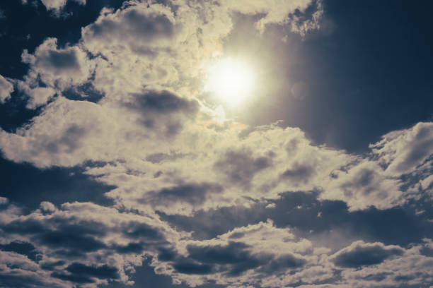 The sun peeks out from behind cumulus clouds. Anxious mood.