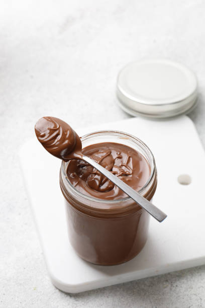 istock Spoon with Chocolate sauce on glass jar and white board. Liquid chocolate. Copy space 1395486911
