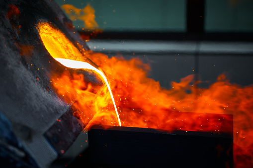 Pouring liquid gold into graphite casting form from furnace