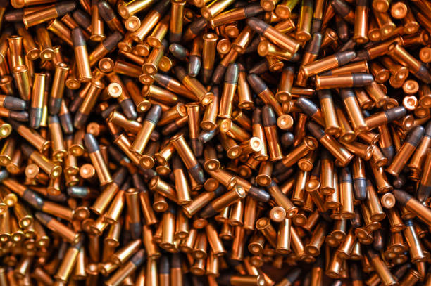 Heap of black and golden small-caliber bullets on table stock photo