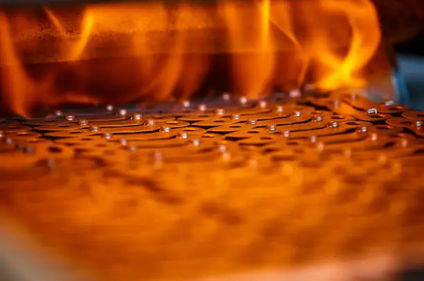 Annealing powdered details with bright burning flame in furnace at metalwork workshop of production plant extreme close view