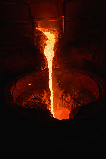 A stream of molten slag is poured into a metallurgical ladle.