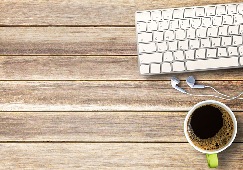 Mini keyboard wireless and cup of coffee,ear phone on wood table background. Top view with copy space for your design.