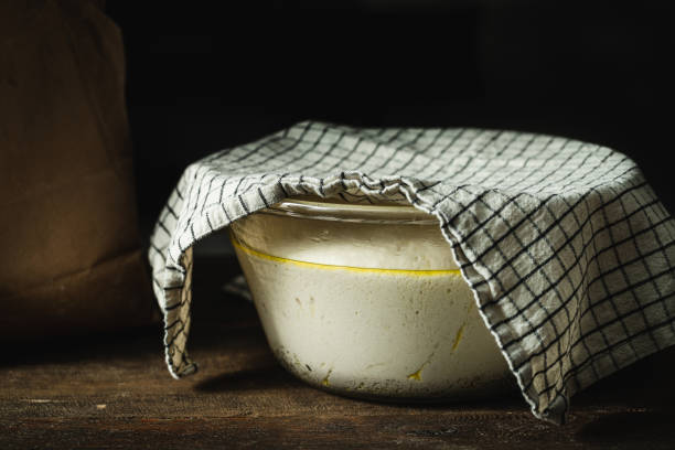 Focaccia bread dough rising in a glass bowl covered with a cloth
