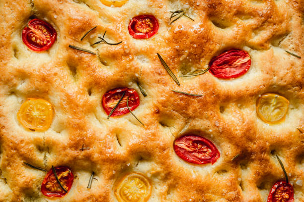 Full frame of freshly baked focaccia bread with tomato and rosemary. Close-up of homemade Italian focaccia bread.