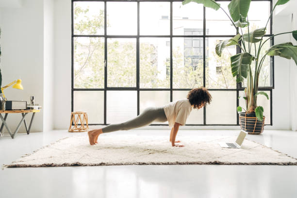 istock Young mixed race woman exercising at home doing plank pose using online video training with laptop. Copy space. 1395493380