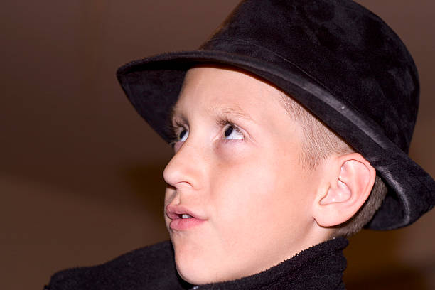 A young boy wearing a cool fedora (hat) looks up