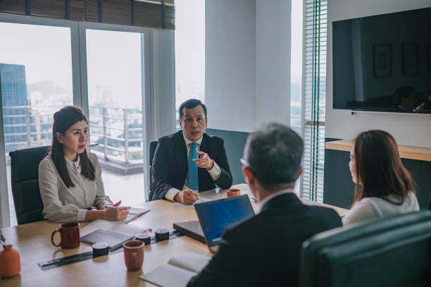 disaccordo tra il capo del dipartimento asiatico nella sala riunioni - ceo serious board room manager foto e immagini stock