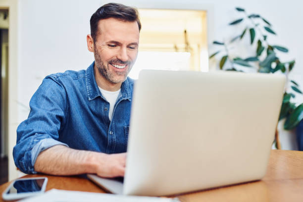 istock Successful man working on laptop sitting at table at home 1395502816