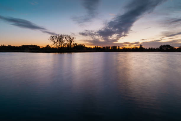 istock Evening colourful clouds after sunset over a calm lake 1395502846