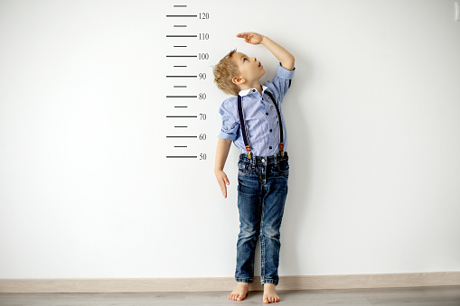Niño pequeño, niño, midiendo la altura contra la pared en la habitación photo