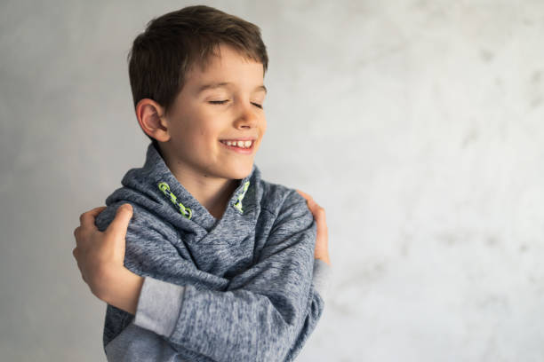 Smiling loving young boy hugging oneself
