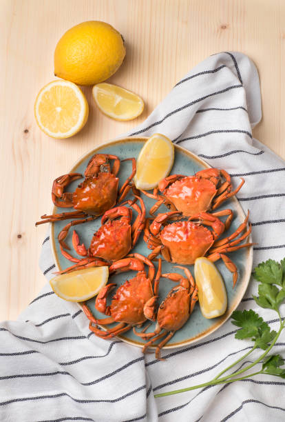 istock Cooked crabs on a blue dish on a light wooden background served with lemons and parsley. Sardinian and Venice Seafood Recipes (cavuru buddiu). Seafood still life, top view 1395509774