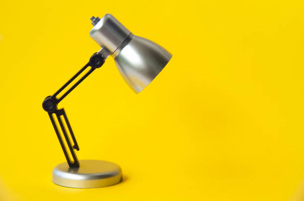 istock Closeup silver and black small lamp on yellow color background. Copy space concept 1395510168