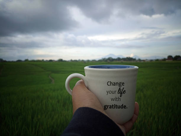 istock Person holding coffee cup in hand with text message - Change your life with gratitude. 1395511987