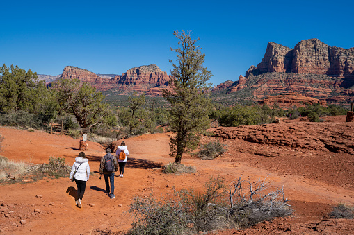 Family hiking in red mountains.Hikers hiking on the footpath in the mountains. People walking on Bell Rock Loop and  Courthouse Butte Loop Trai, just south of Sedona in Yavapai County. Arizona. USA.