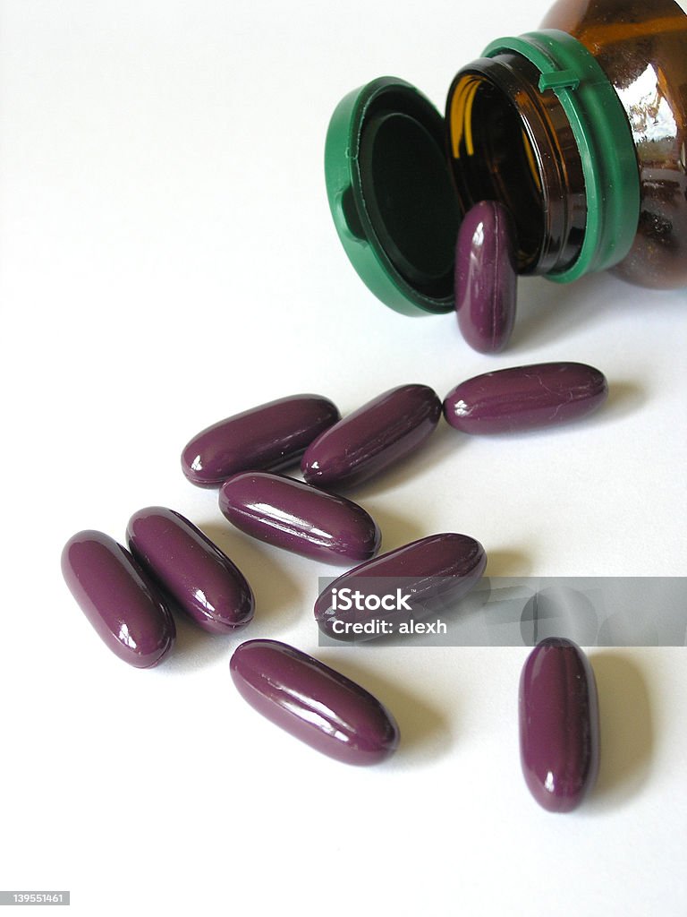 Pill bottle Big purple pills spilling from brown bottle.     Addiction Stock Photo