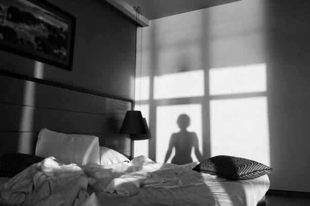 Silhouette of a girl in front of a window, black and white art photography monochrome. Young woman is sitting on the bed, shadow on the wall. Silhouette of a girl in front of a window black and white art photography monochrome, photo noir, retro. sensuality stock pictures, royalty-free photos & images