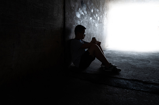 A boy sitting in the dark tunnel.