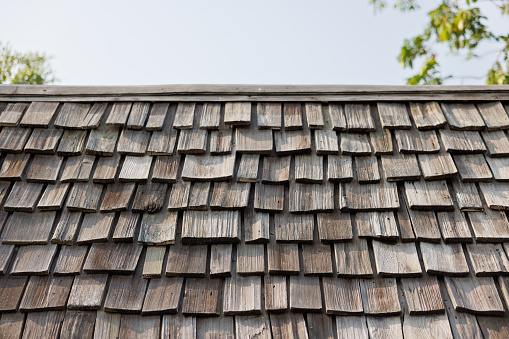 old wooden shingle on rooftop with blue sky.