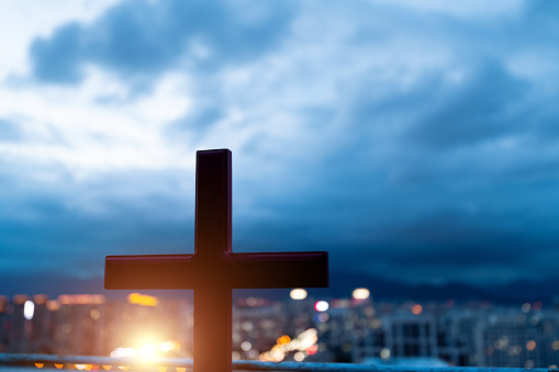 Religious cross on city background.