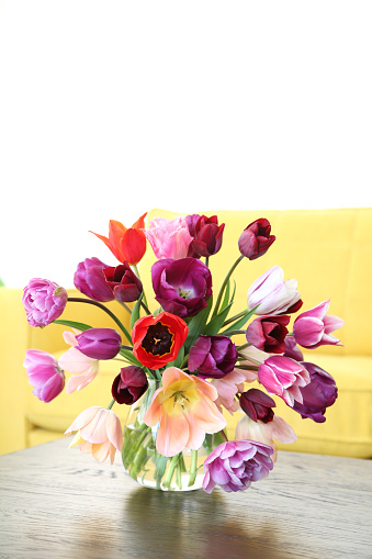Vase full of  colourful flowers on glass table with sofa at modern Cafe