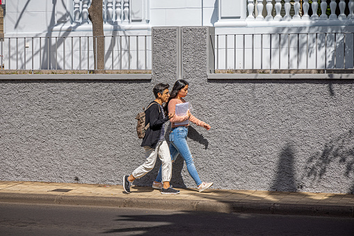 Mother and daughter walking down the street on a sunny day in the center of Santa Cruz which is the main city on the Spanish Canary Island Tenerife