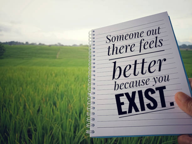 istock Person holding notebook in hand with text message - Someone out there feels better because you exist. 1395525415