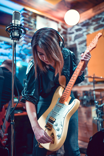 Female Guitarist Preparing Guitar For Performance With Her Band